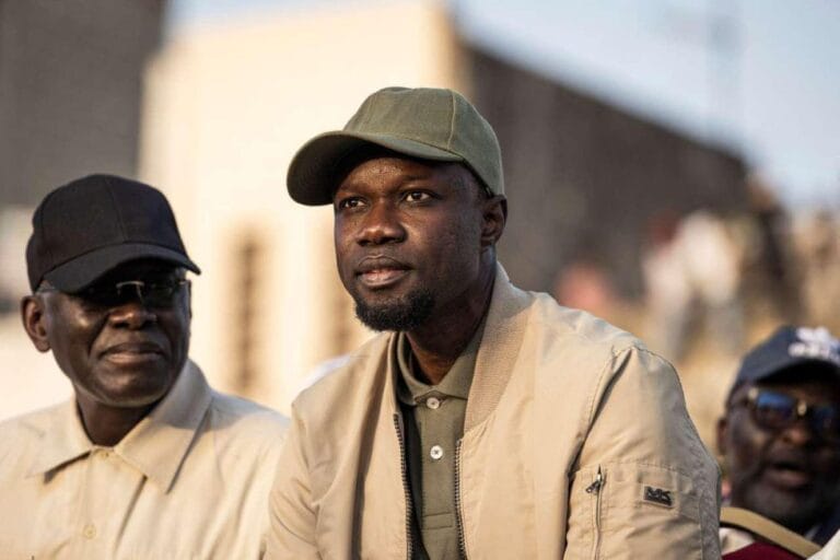 Portrait de l'homme politique sénégalais Habib Sy en costume traditionnel, s'exprimant derrière un micro lors d'une conférence de presse à Dakar.