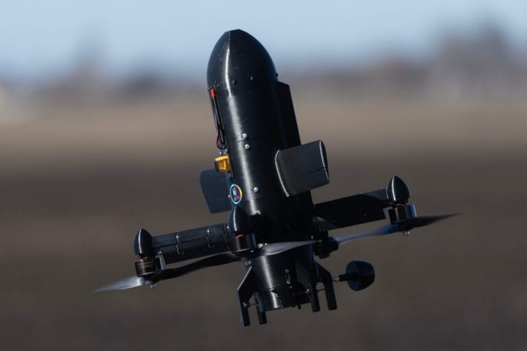 Un drone de combat de type quadrirotor équipé pour des missions de reconnaissance tactique en zone désertique.
